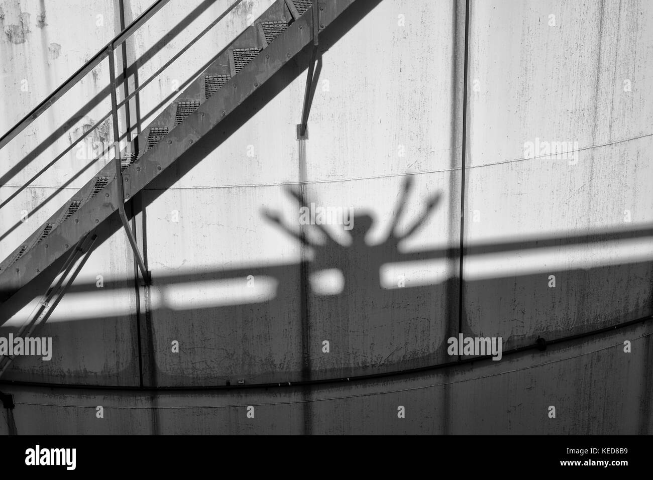 Persone ombre sui vecchi serbatoi in metallo in Power Plant, il vecchio tipo di impianto di fabbrica. struttura in metallo con la vecchia vernice gialla e rusty luoghi. cerchio di ferro la Foto Stock