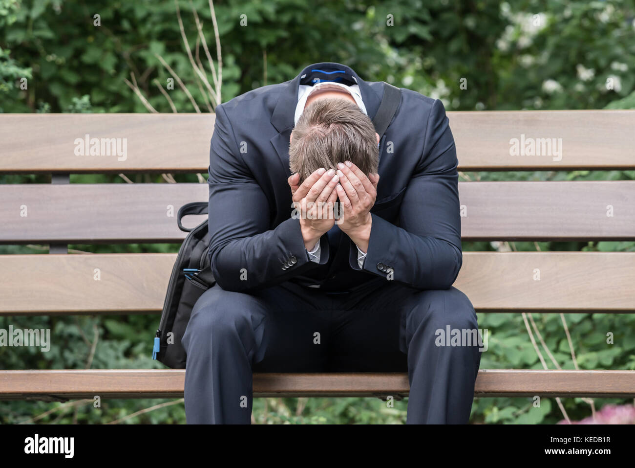 Triste giovane impreditore seduta sul banco che soffrono di mal di testa Foto Stock