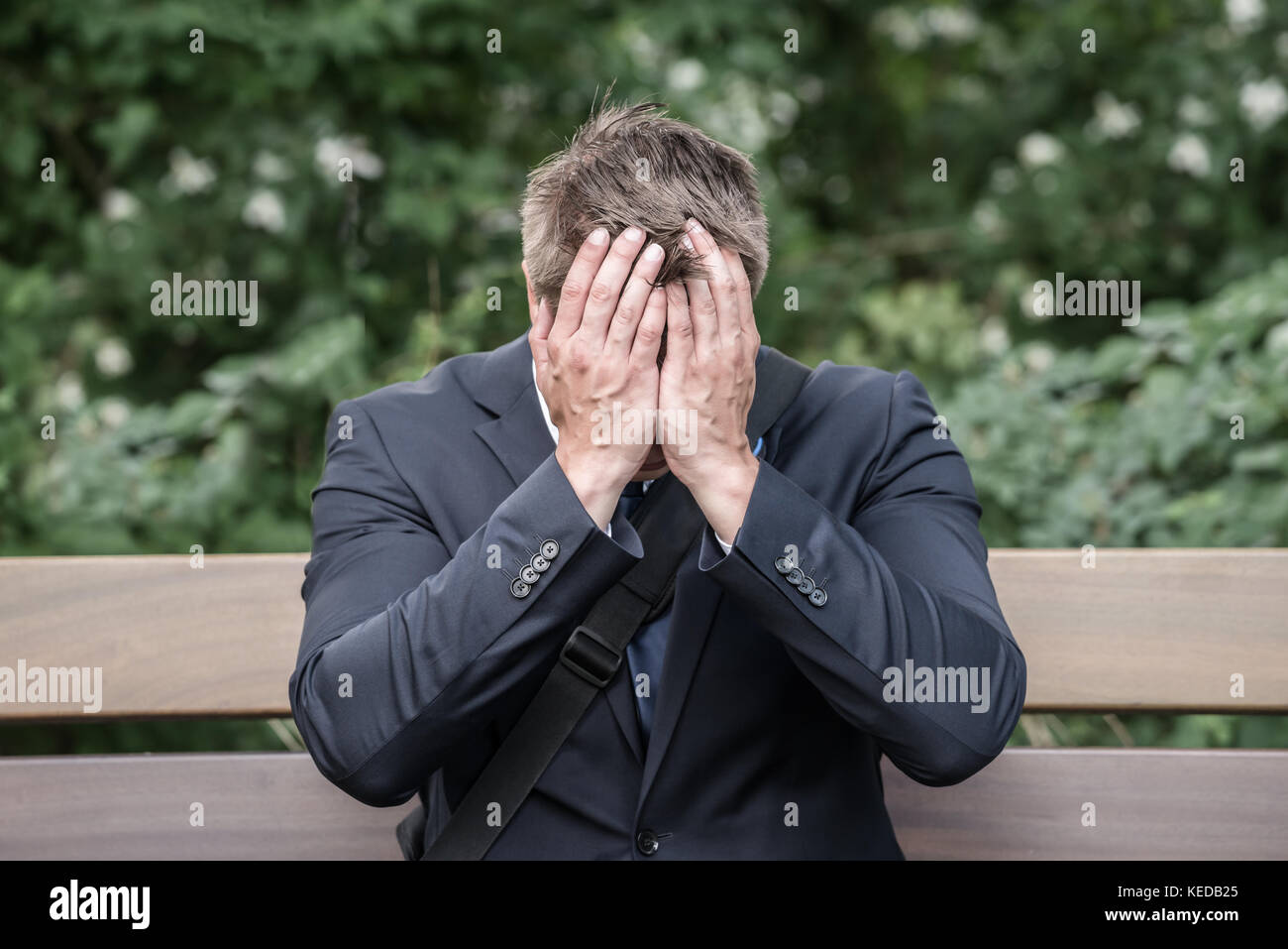 Triste giovane impreditore seduta sul banco che soffrono di mal di testa Foto Stock