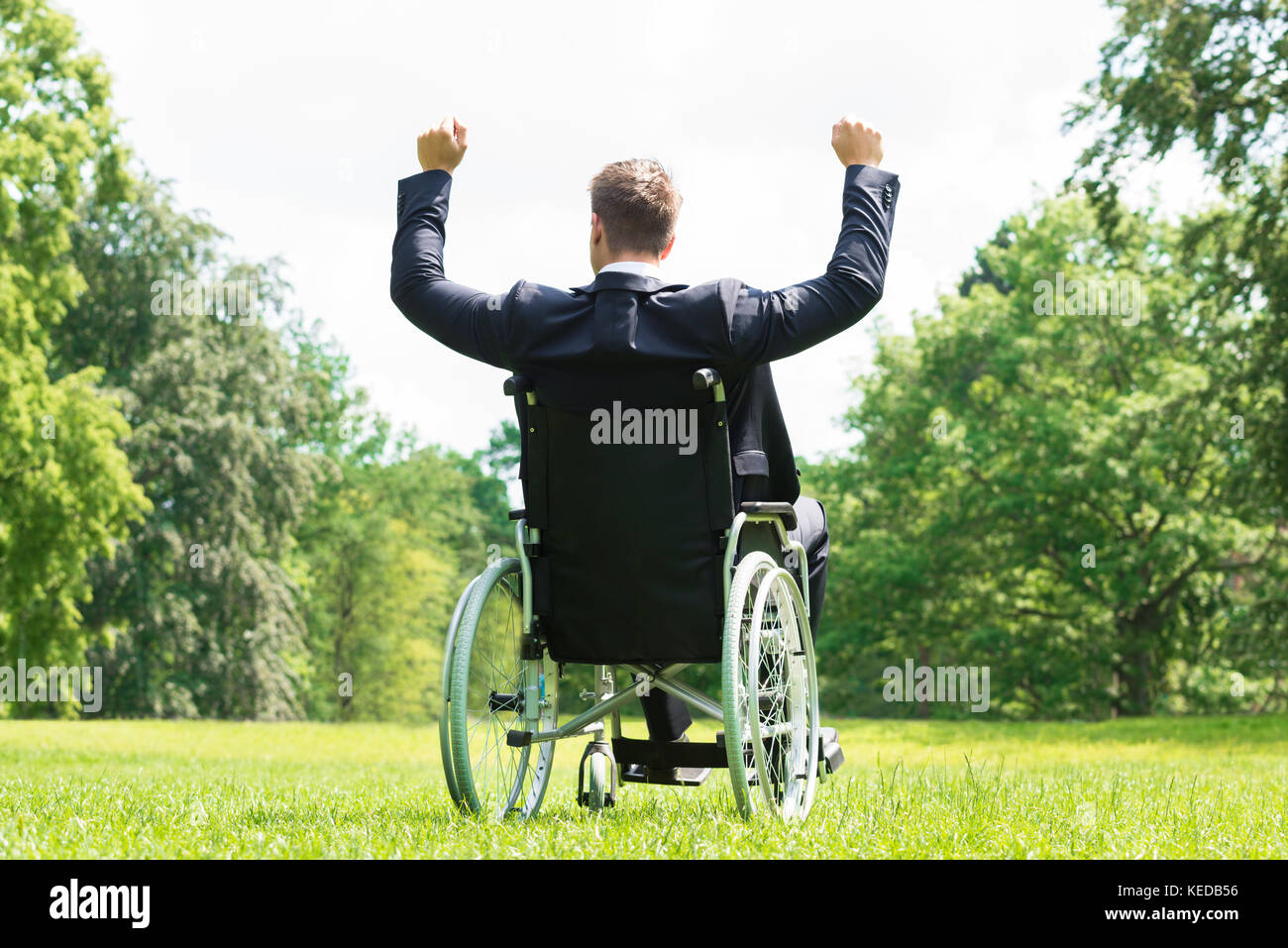 Vista posteriore del giovane uomo disabili su sedia a rotelle con il braccio sollevato in posizione di parcheggio Foto Stock