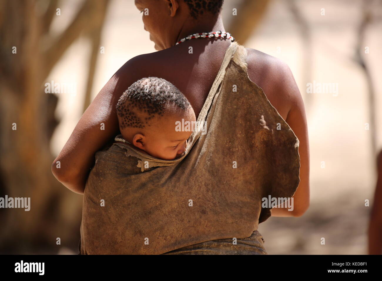 San Buschmänner persone in Namibia - Volksstamm - Donna con bambino sul retro Foto Stock