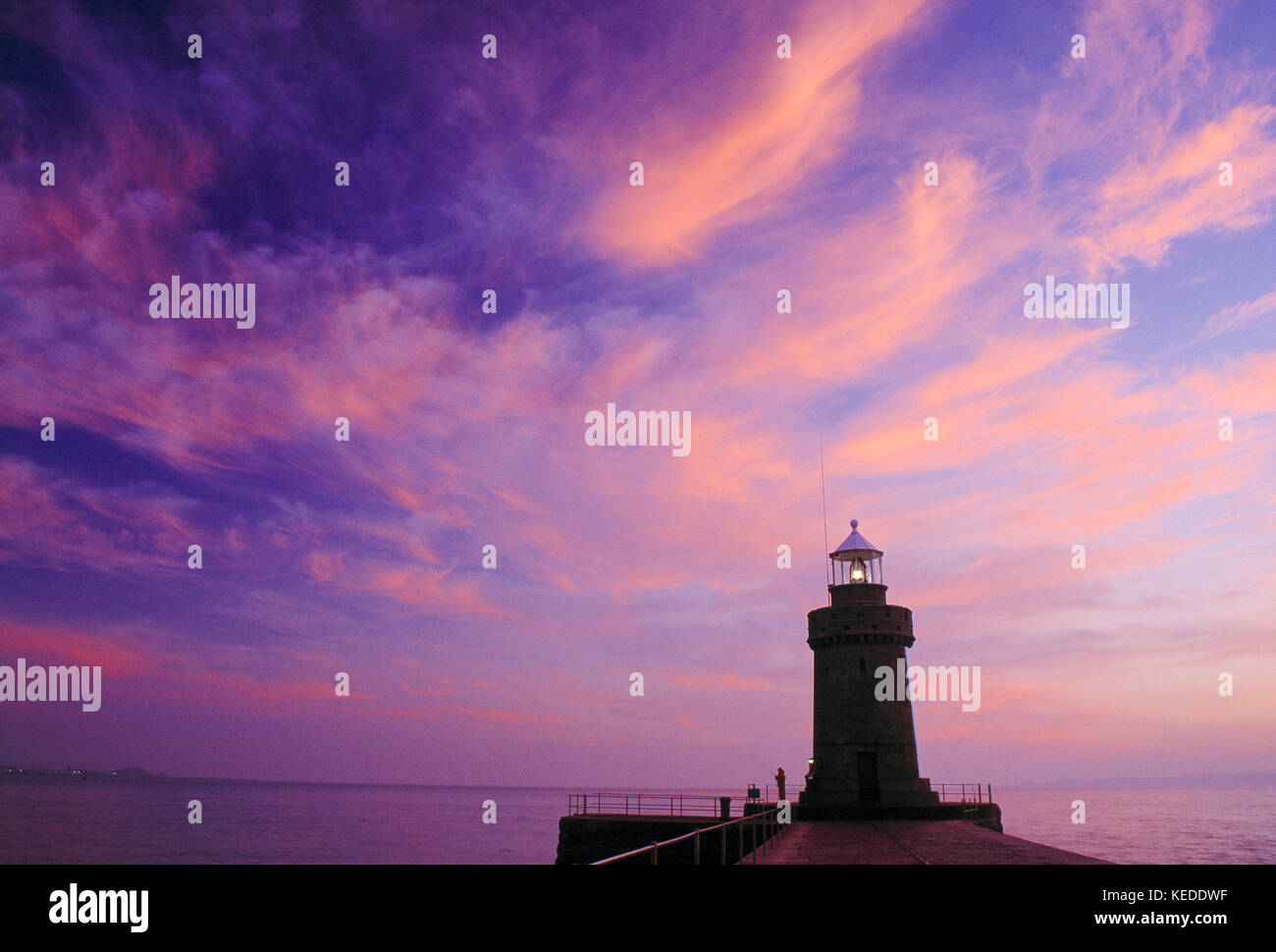 Guernsey. Porto di San Pietro. Frangiflutti del castello e faro all'alba. Foto Stock