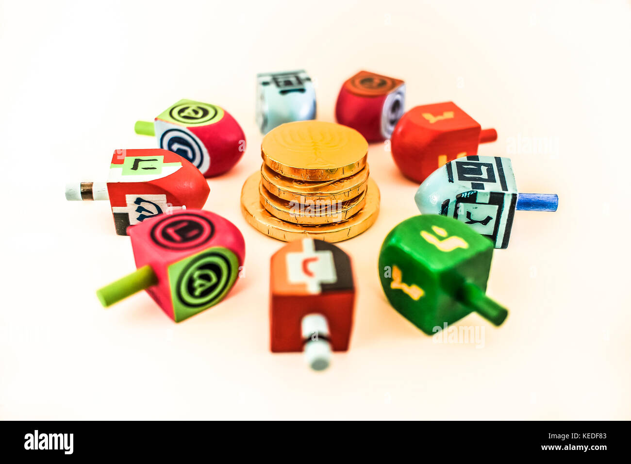 Denaro gelt e dreidels disposti in un cerchio isolato su sfondo bianco; celebrazione Ebraica Foto Stock