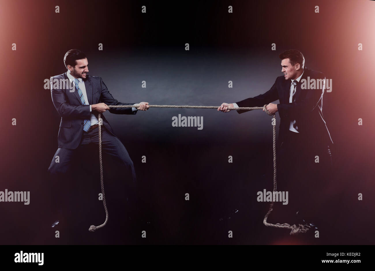 Due uomini di affari tirando la corda in una competizione, isolati su sfondo bianco Foto Stock