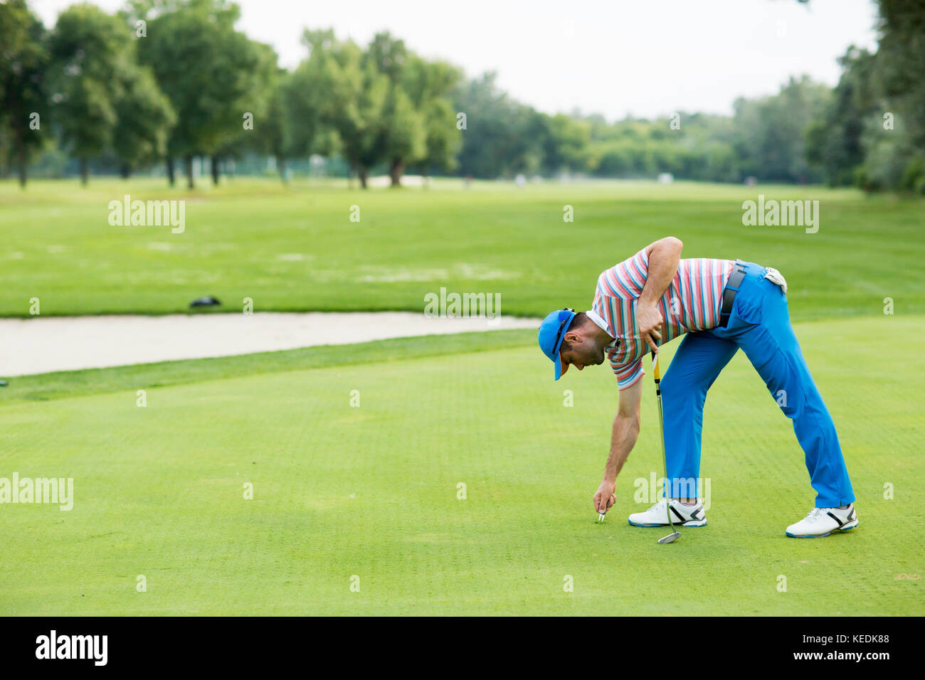 Giovane uomo per giocare a golf in una giornata di sole su un bellissimo campo da golf Foto Stock