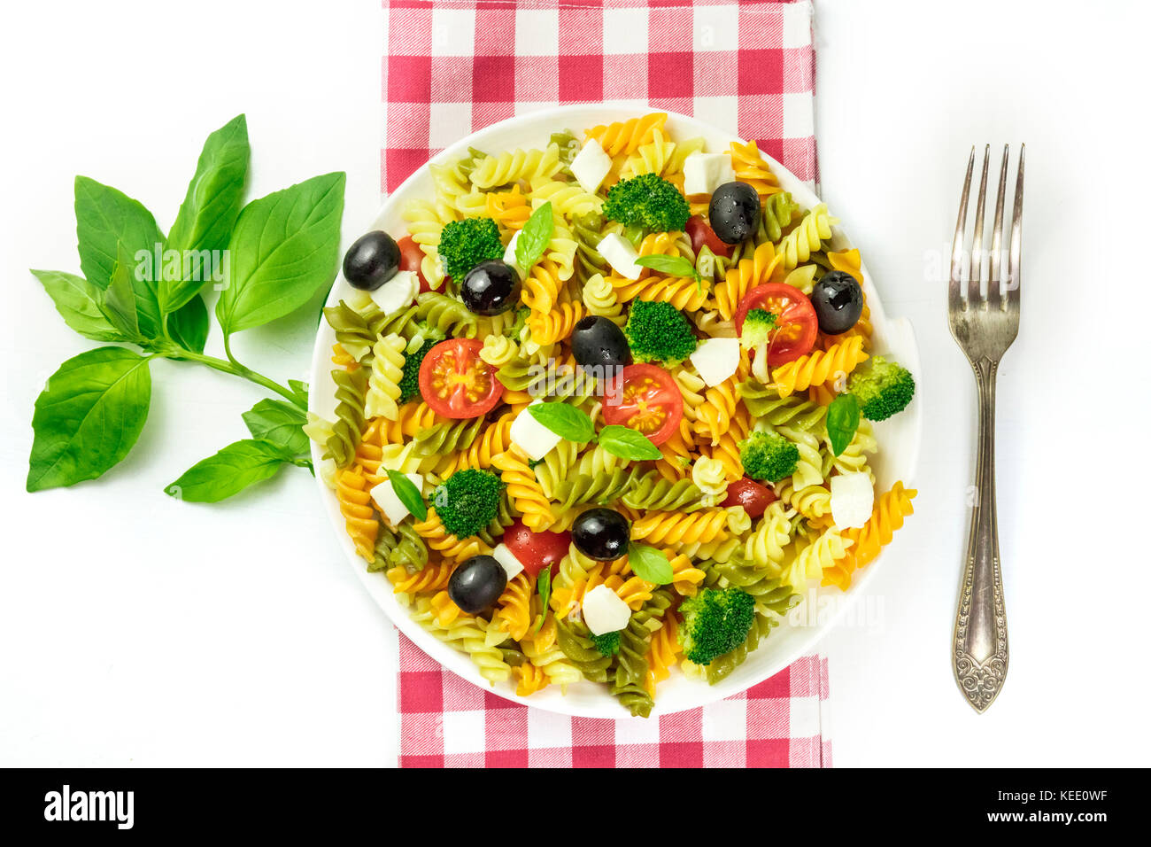 Insalata di pasta con foglie di basilico e la forcella su bianco Foto Stock