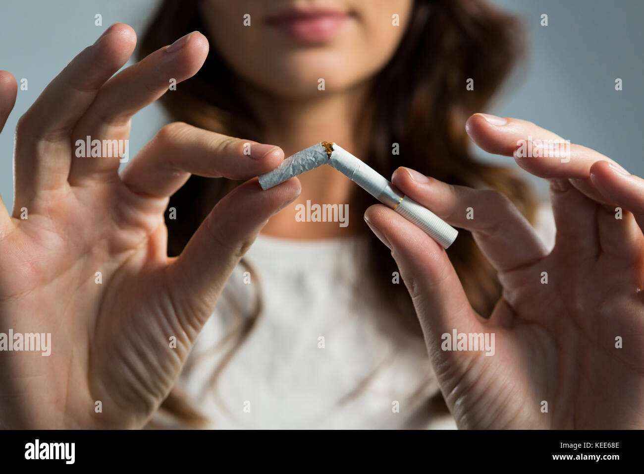 La sezione centrale della donna la rottura sigaretta contro uno sfondo bianco Foto Stock