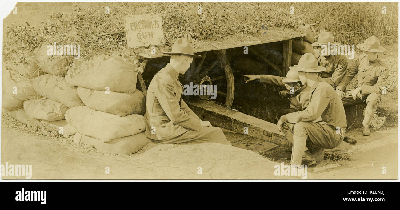 Cinque soldati riuniti intorno e imparare a conoscere un mimetizzata artiglieria francese pistola 75. Foto Stock