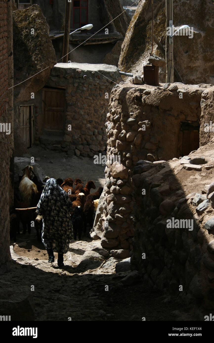 8 maggio 2008 - Kandovan, Provincia di Kandovan Azerbaigian, Iran - UNA donna locale è raffigurata mentre cammina attraverso il vicolo stretto all'interno del villaggio.. Il piccolo villaggio di Kandovan (aka Kanvan), nella provincia dell'Azerbaigian orientale iraniano è conosciuto per le sue abitazioni di scogliera, non costruito sulle formazioni rocciose, ma scolpito nelle rocce vulcaniche stesse. Le formazioni rocciose a forma di cono sono dovute all'erosione dell'acqua della matrice acida porosa, sviluppata dopo l'eruzione del Monte Sahand nel Distretto Centrale della Contea di Osku. Le rocce agiscono anche come un materiale efficiente dal punto di vista energetico, mantenendo le case calde Foto Stock