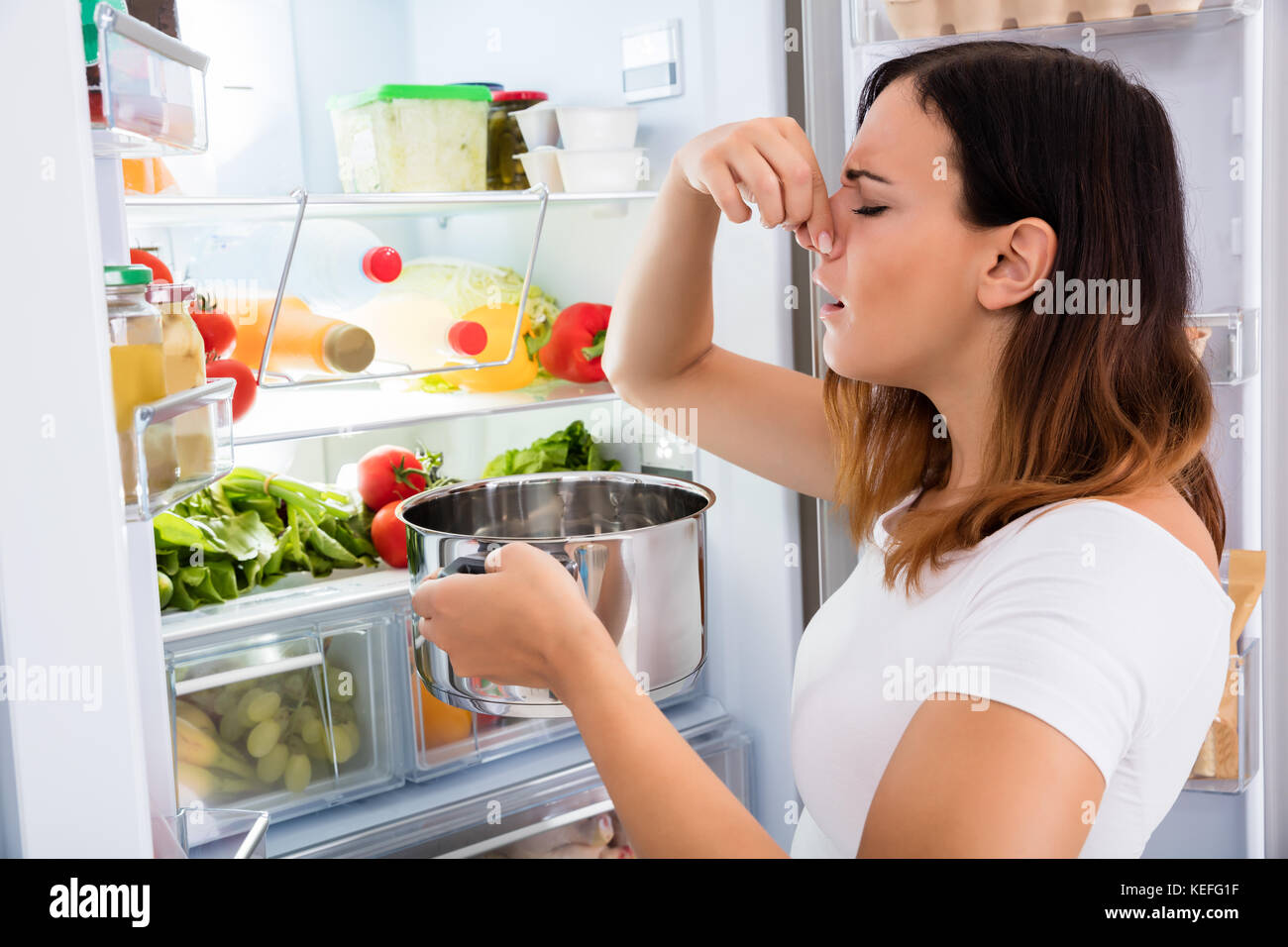 Giovane donna notato puzza di cibo vicino al frigorifero aperto Foto Stock