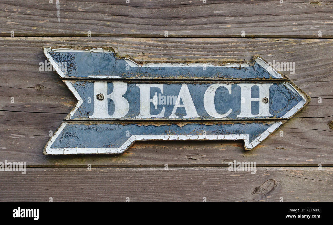 Vintage blu e bianco a forma di orientamento come una freccia dicendo "spiaggia" su pannello in legno parete Foto Stock