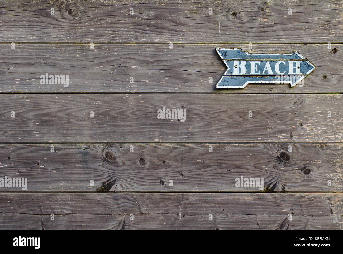 Vintage blu e bianco a forma di orientamento come una freccia dicendo "spiaggia" su pannello in legno parete Foto Stock