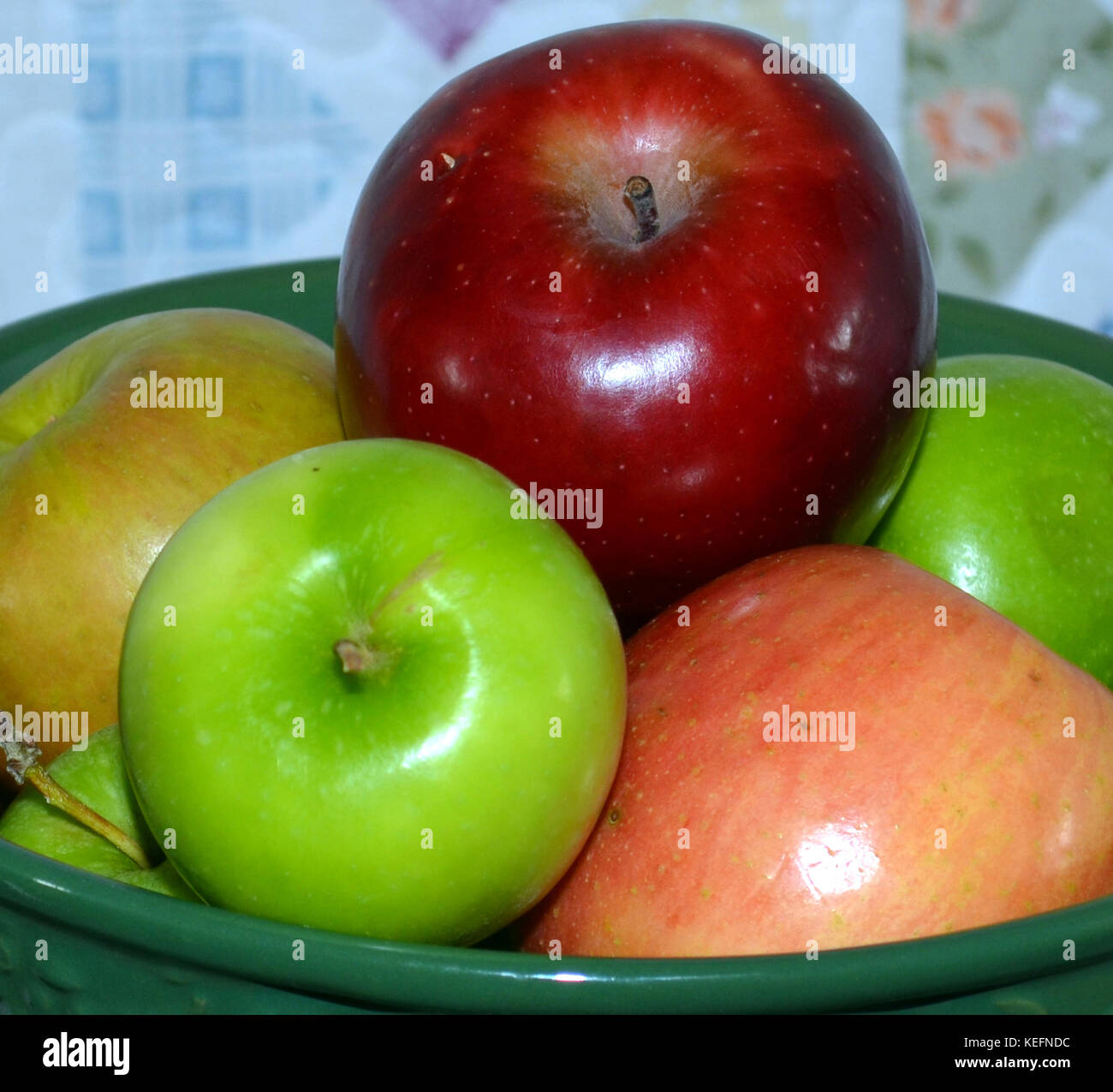 Multicolore di mele in un recipiente verde con una trapunta in background. Foto Stock