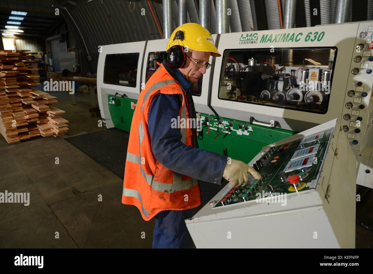 Lavoratori utilizzano un quattro sider macchina al piano bordi ruvidi da quattro lati di grandi tavole di pino in una lavorazione del legno fabbrica vicino a Greymouth, Nuova Zelanda Foto Stock