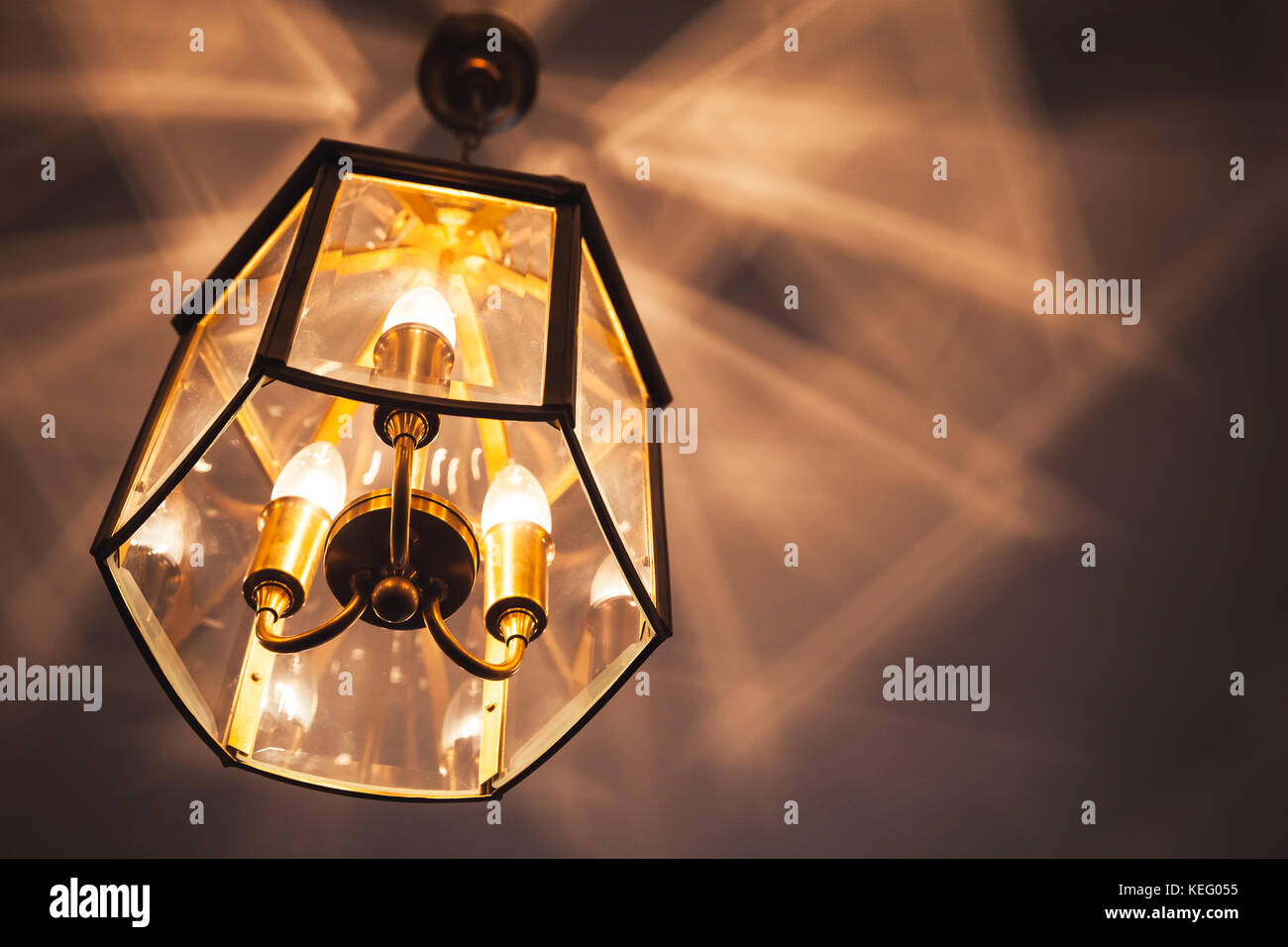 Vecchio lampadario con una calda luce gialla appesa al soffitto e crea ombre artistico pattern Foto Stock