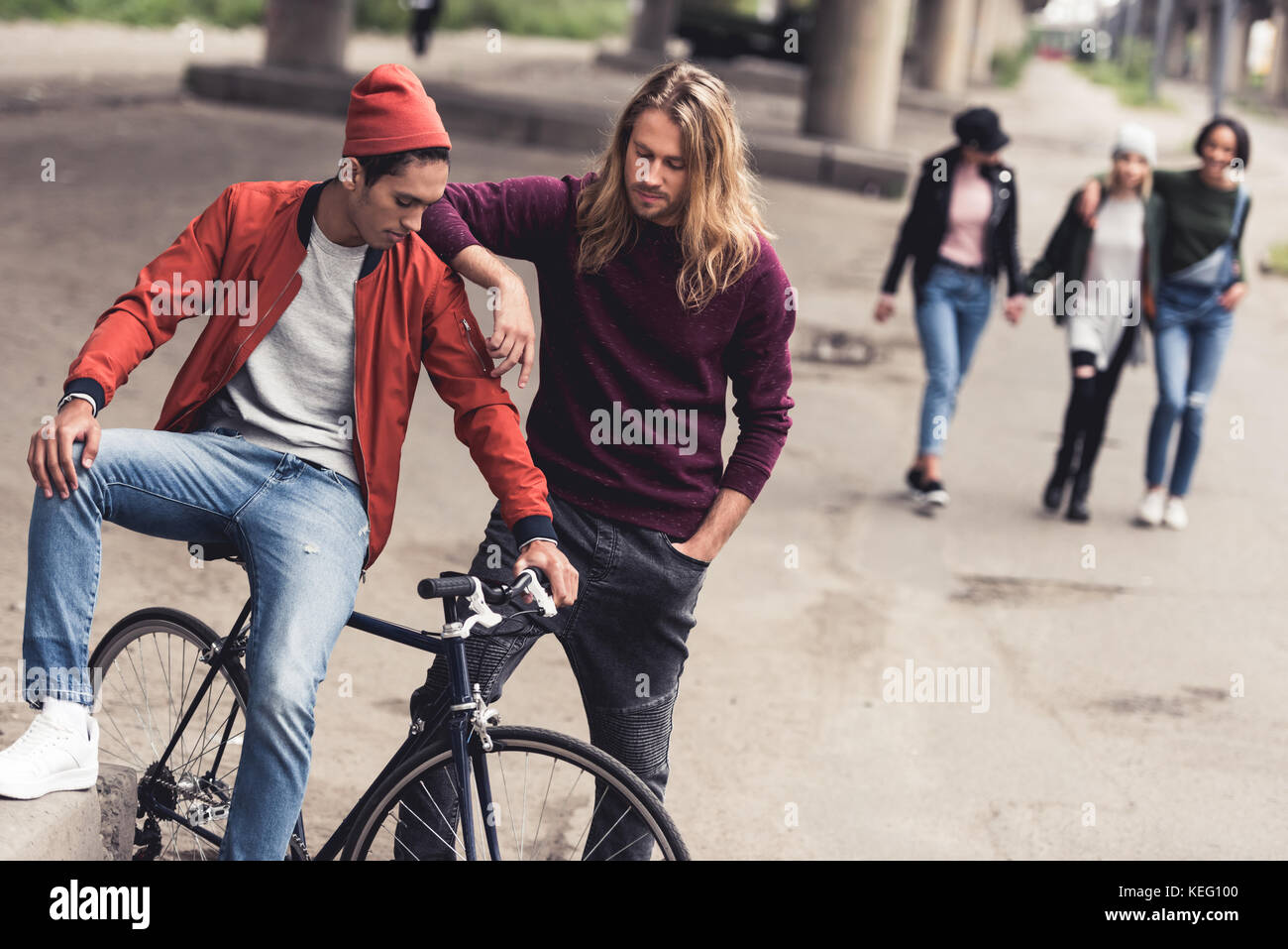 Giovani uomini belli con bici vintage e donne eleganti passeggiate sfocato  sullo sfondo Foto stock - Alamy