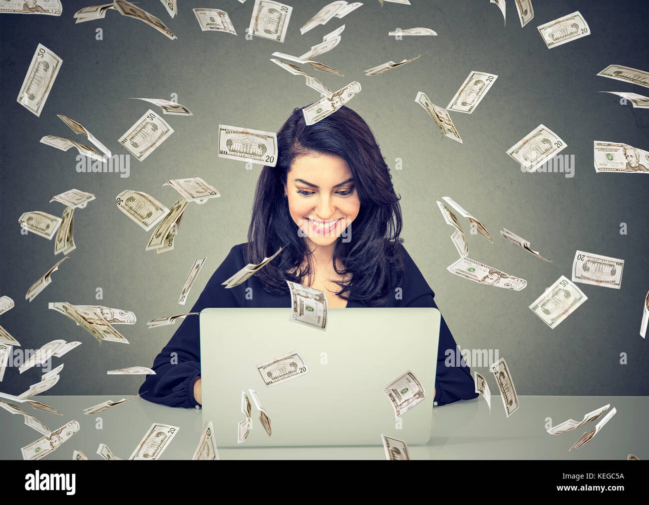 Felice Donna che utilizza un computer portatile building online business sotto le fatture del dollaro cadere. denaro pioggia di imprenditore di successo il concetto di economia Foto Stock