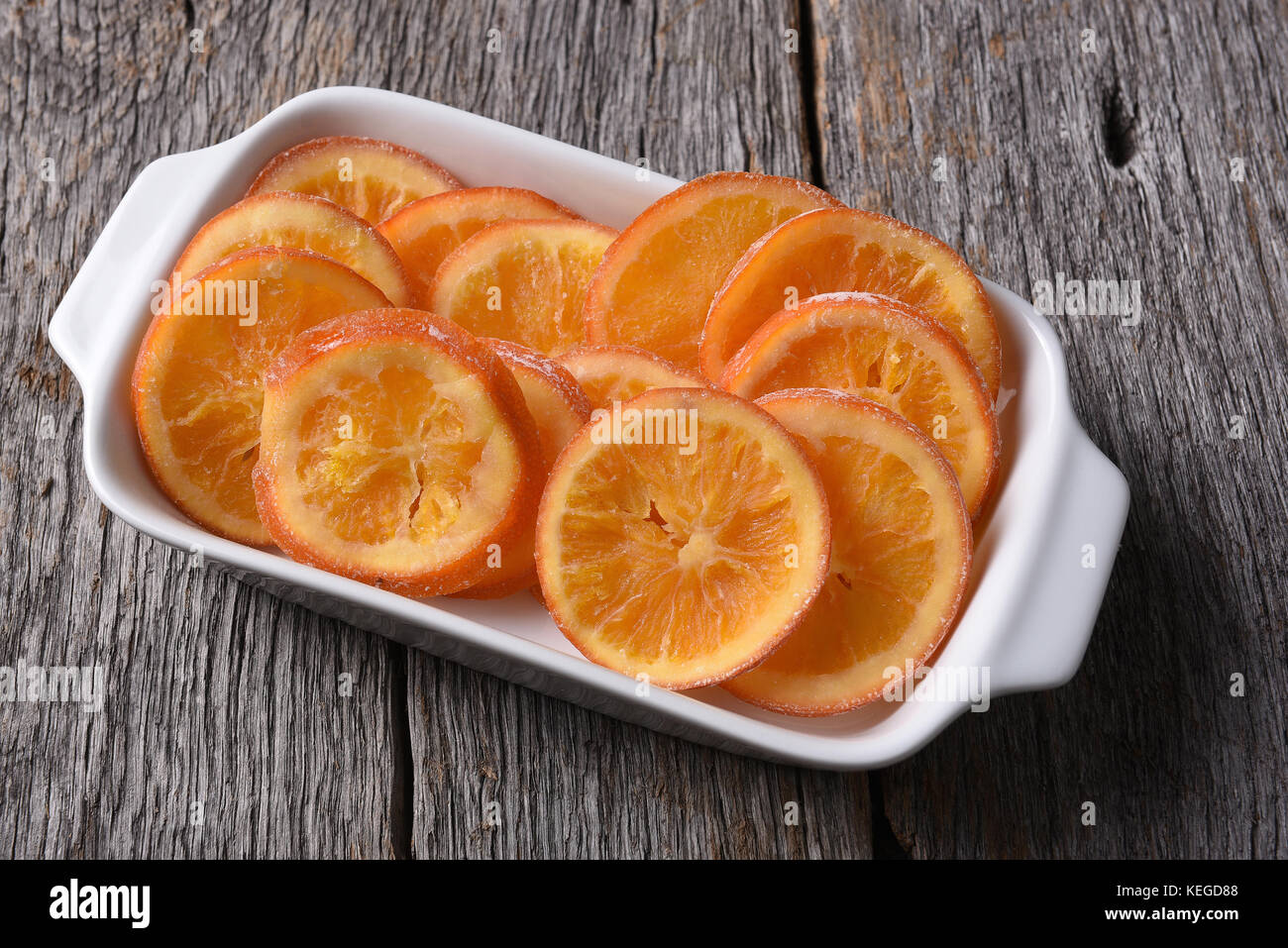 Un rettangolo piatto di essiccato addolcito fettine di arancia su di un legno rustico superficie. Foto Stock
