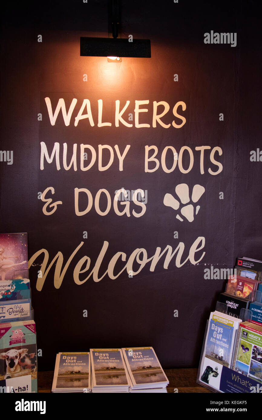 Scuotipaglia, cani e fangoso stivali segno di benvenuto in un pub di campagna, England, Regno Unito Foto Stock