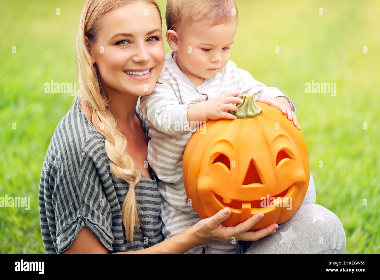 Closeup ritratto di una giovane e bella madre con la sua preziosa piccolo figlio di preparare per la sua prima vacanza di halloween, giocando con la zucca, divertimento per tutta la famiglia Foto Stock