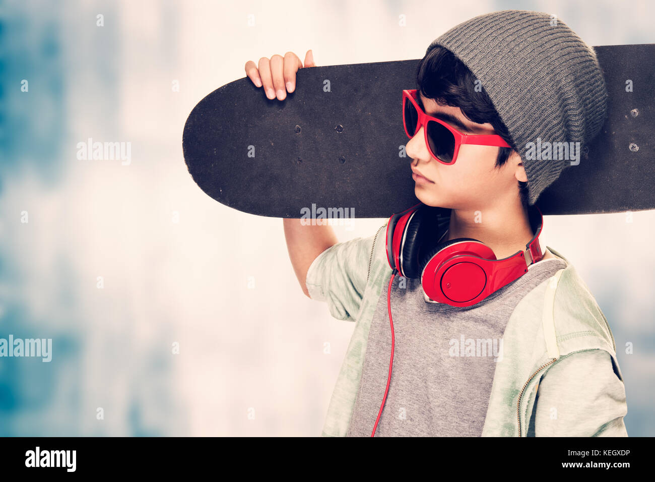 Ritratto di un elegante teen boy indossando occhiali da sole e cappello  tenendo in mano lo skateboard su sfondo grunge, la vita moderna della  gioventù Foto stock - Alamy