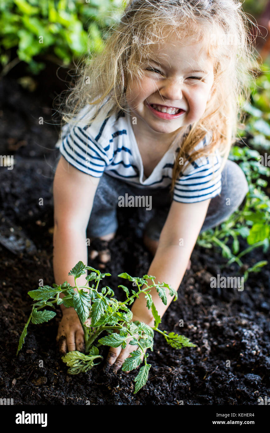 Caucasica ragazza in posa con pianta in giardino Foto Stock