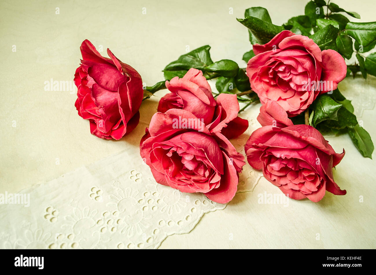 Angolo con un mazzo di rose rosse giacente sul bianco ricamato openwork una striscia di tessuto Foto Stock