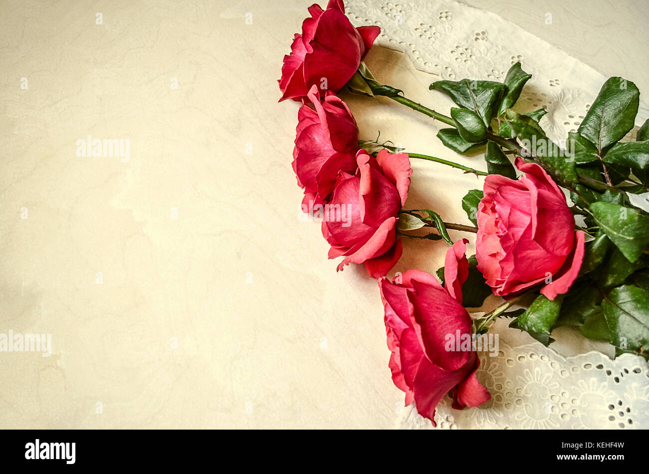 Aperto a metà rose rosse con ricamato striscia traforata giaceva sul legno compensato Foto Stock
