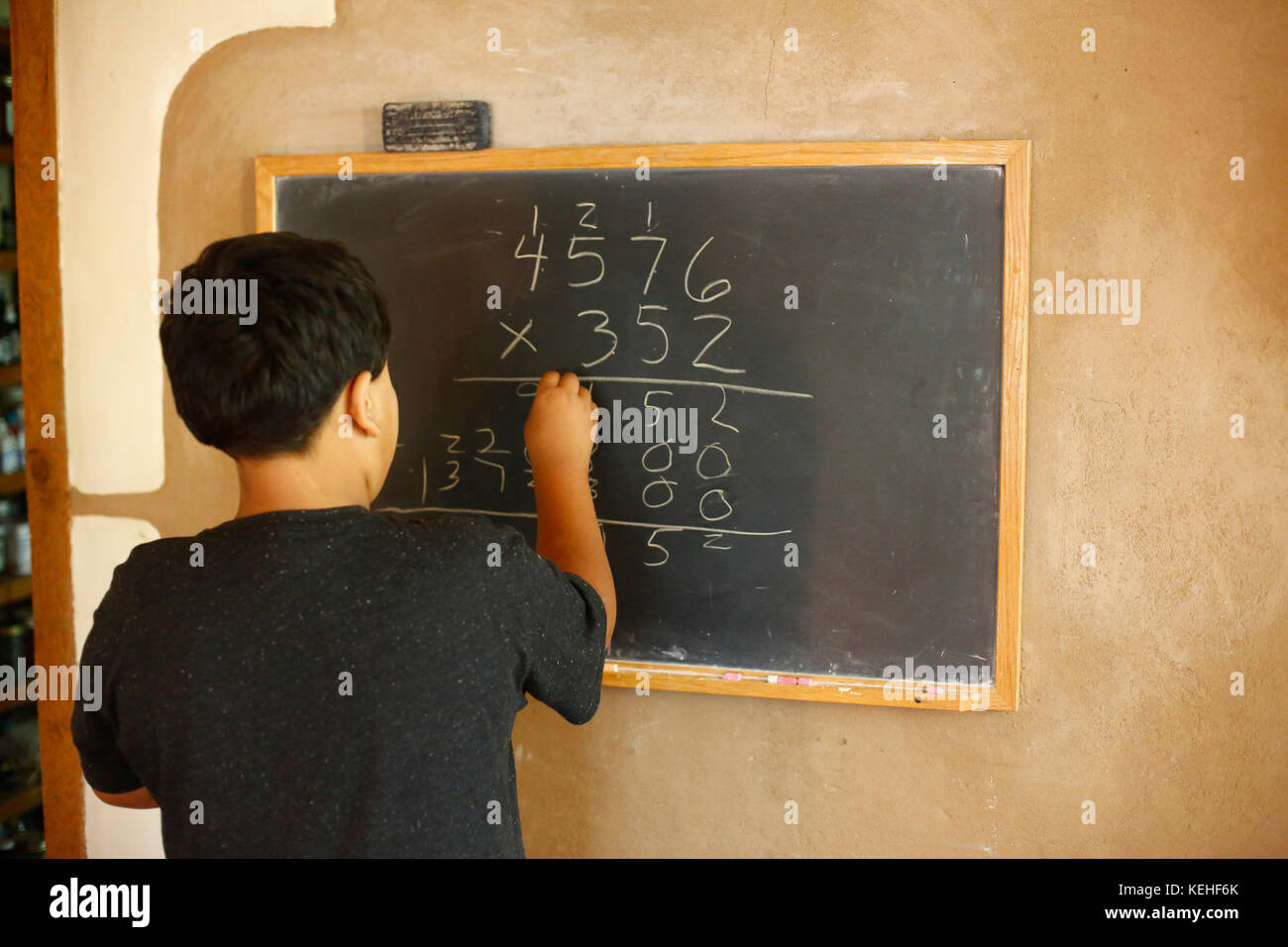 Equazione di risoluzione del ragazzo nativo americano sulla lavagna Foto Stock