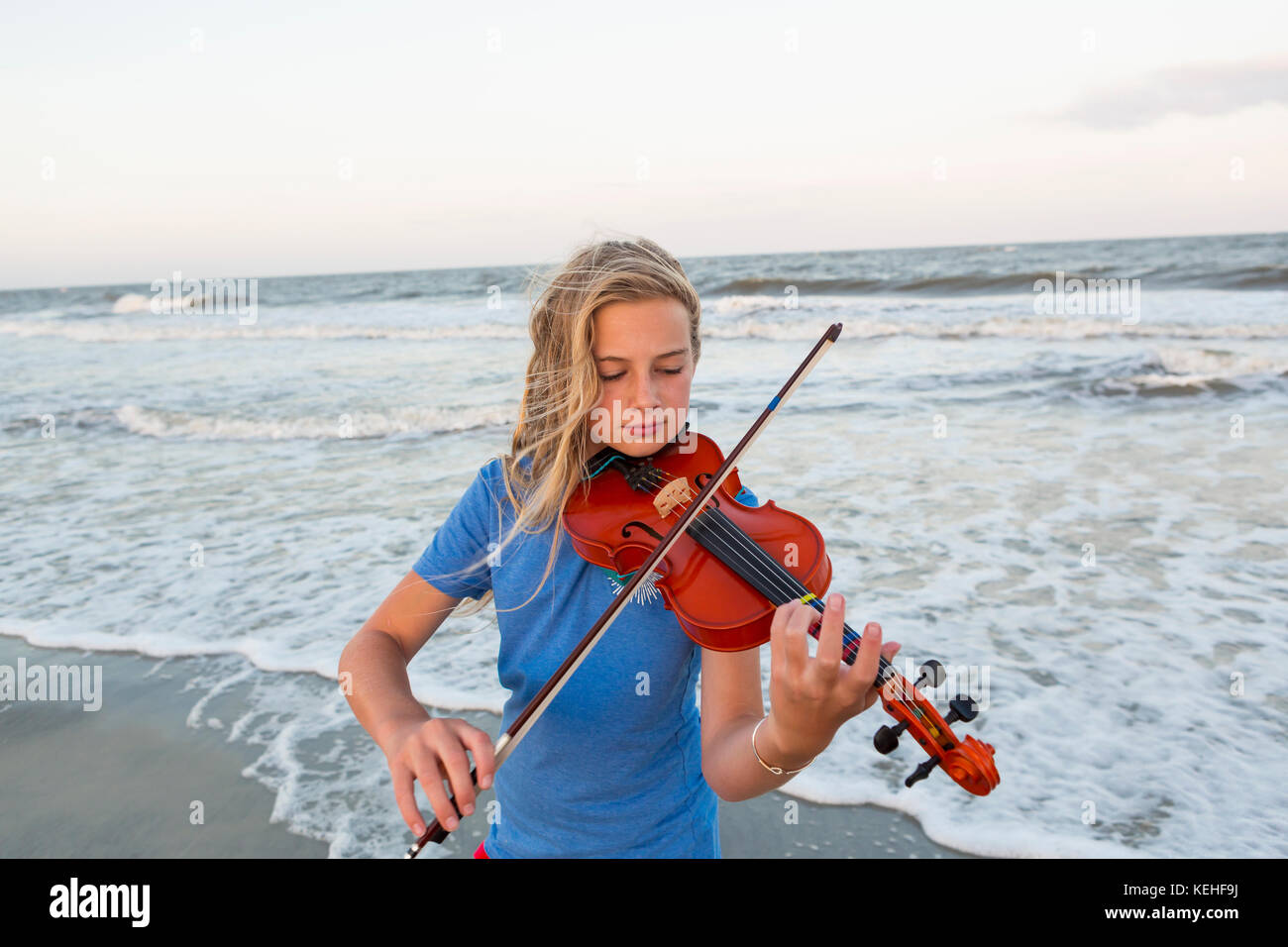 Caucasica ragazza che suona violino in spiaggia Foto Stock
