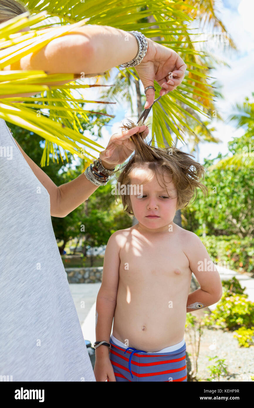 Madre caucasica che taglia i capelli del figlio all'aperto Foto Stock