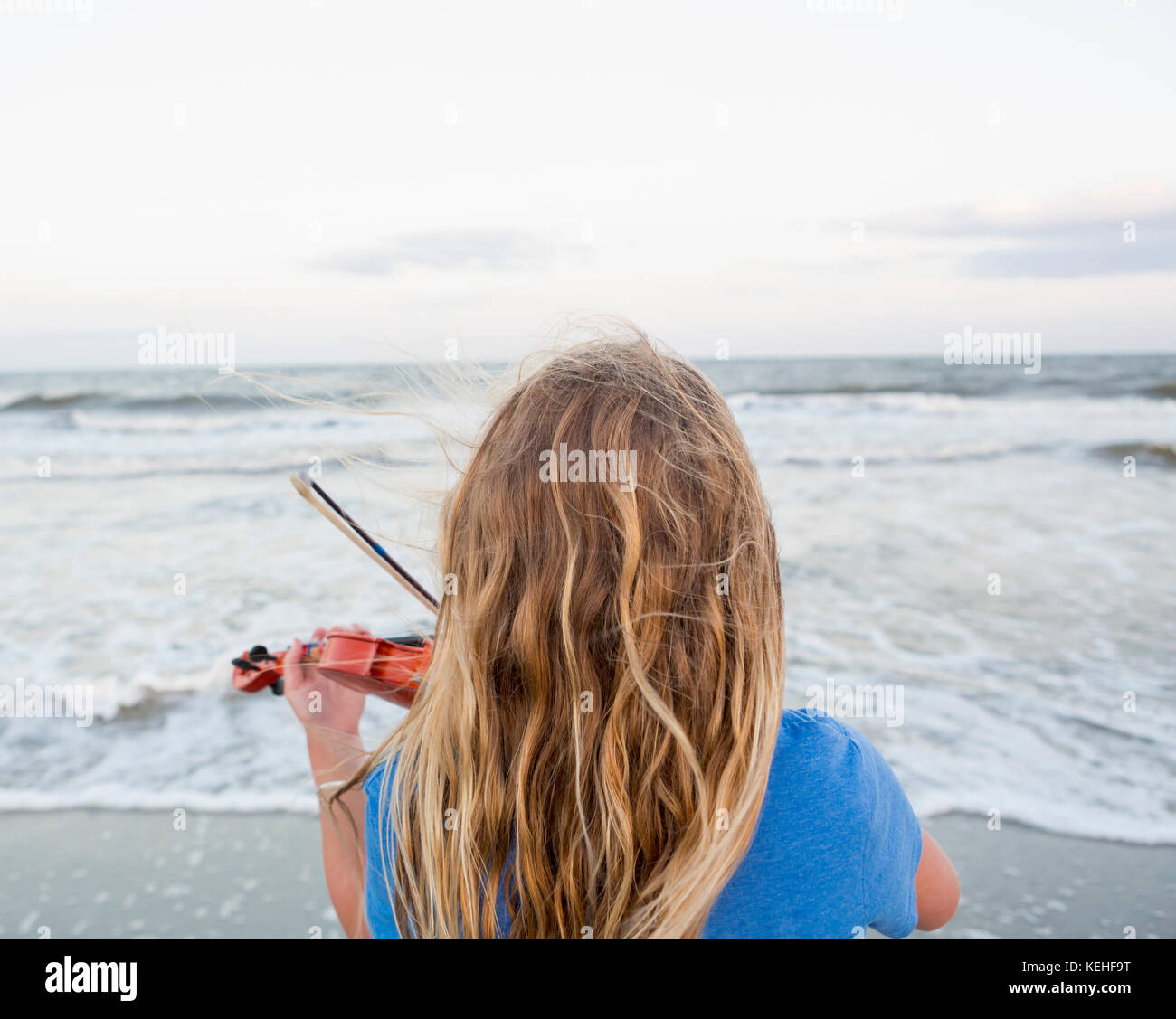 Vista posteriore della ragazza caucasica che suona violino in spiaggia Foto Stock