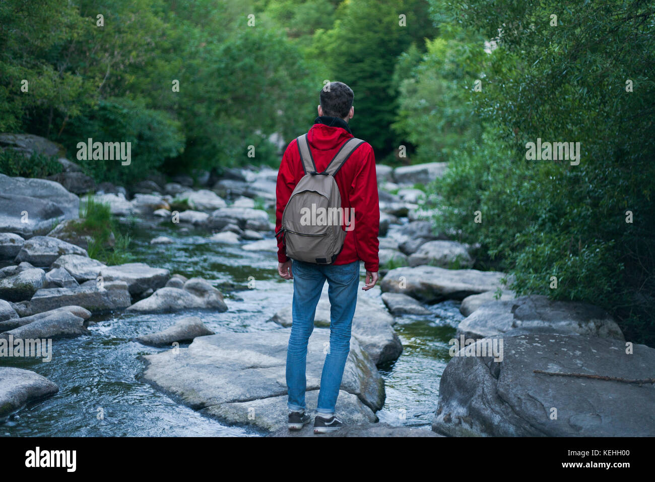 Uomo caucasico in piedi sulla roccia nel fiume Foto Stock