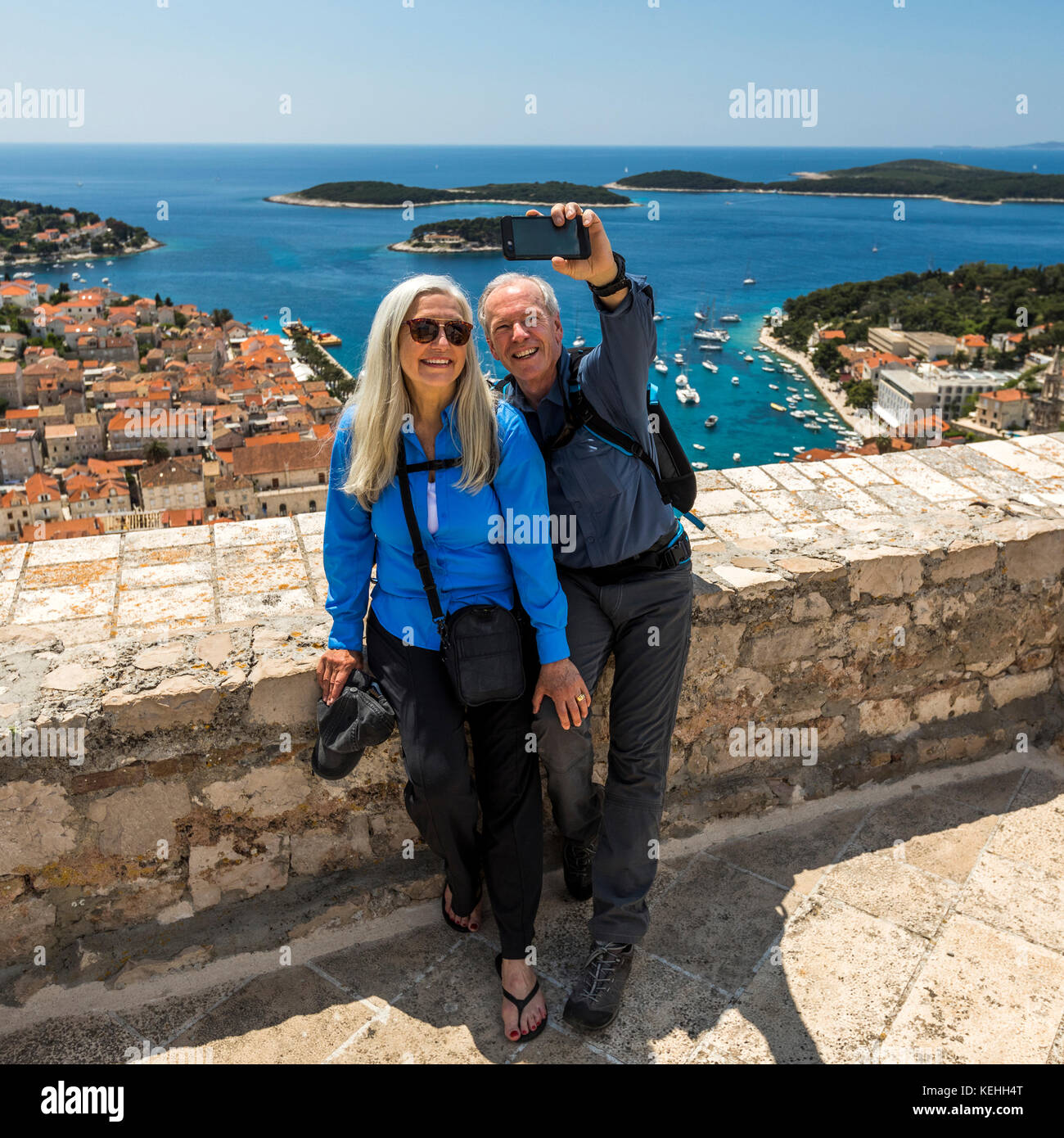 Coppia caucasica in posa per selfie di telefono cellulare con vista panoramica dell'oceano Foto Stock