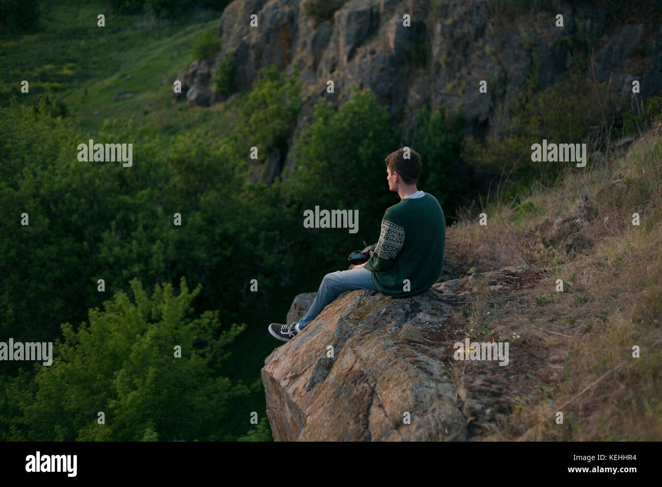 Uomo caucasico seduto su una roccia che ammira il paesaggio Foto Stock