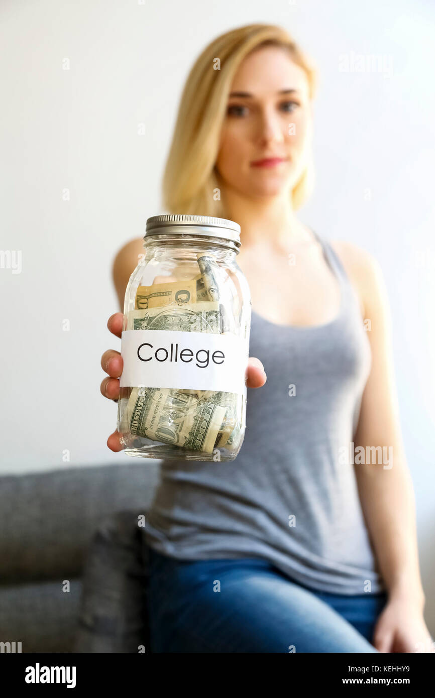 Donna caucasica che mostra vaso di soldi per l'università Foto Stock