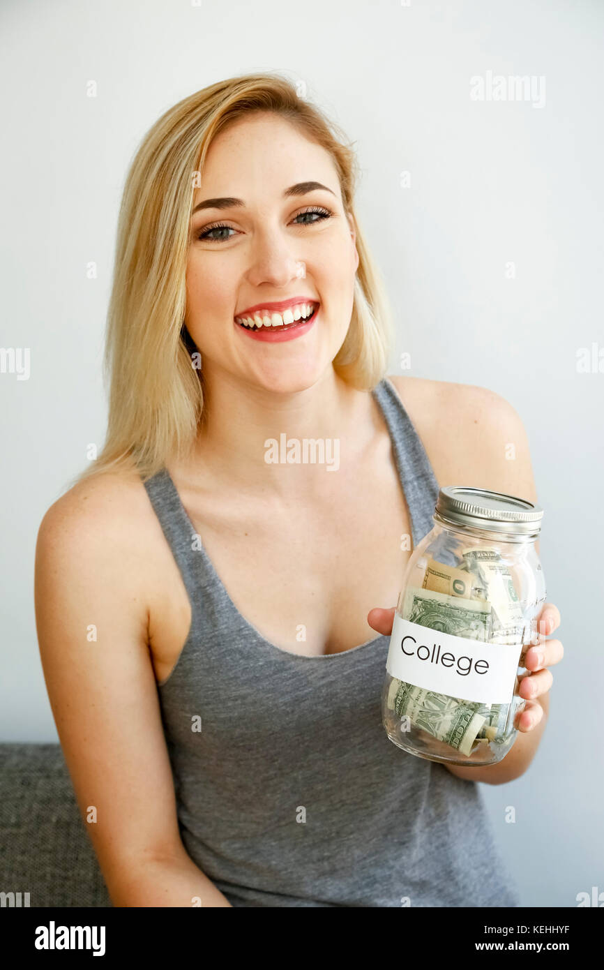Donna caucasica che mostra vaso di soldi per l'università Foto Stock