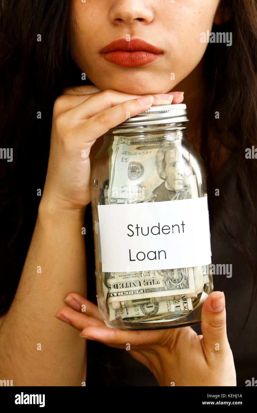 Ritratto di donna di razza mista che tiene vaso di denaro per prestito studente Foto Stock