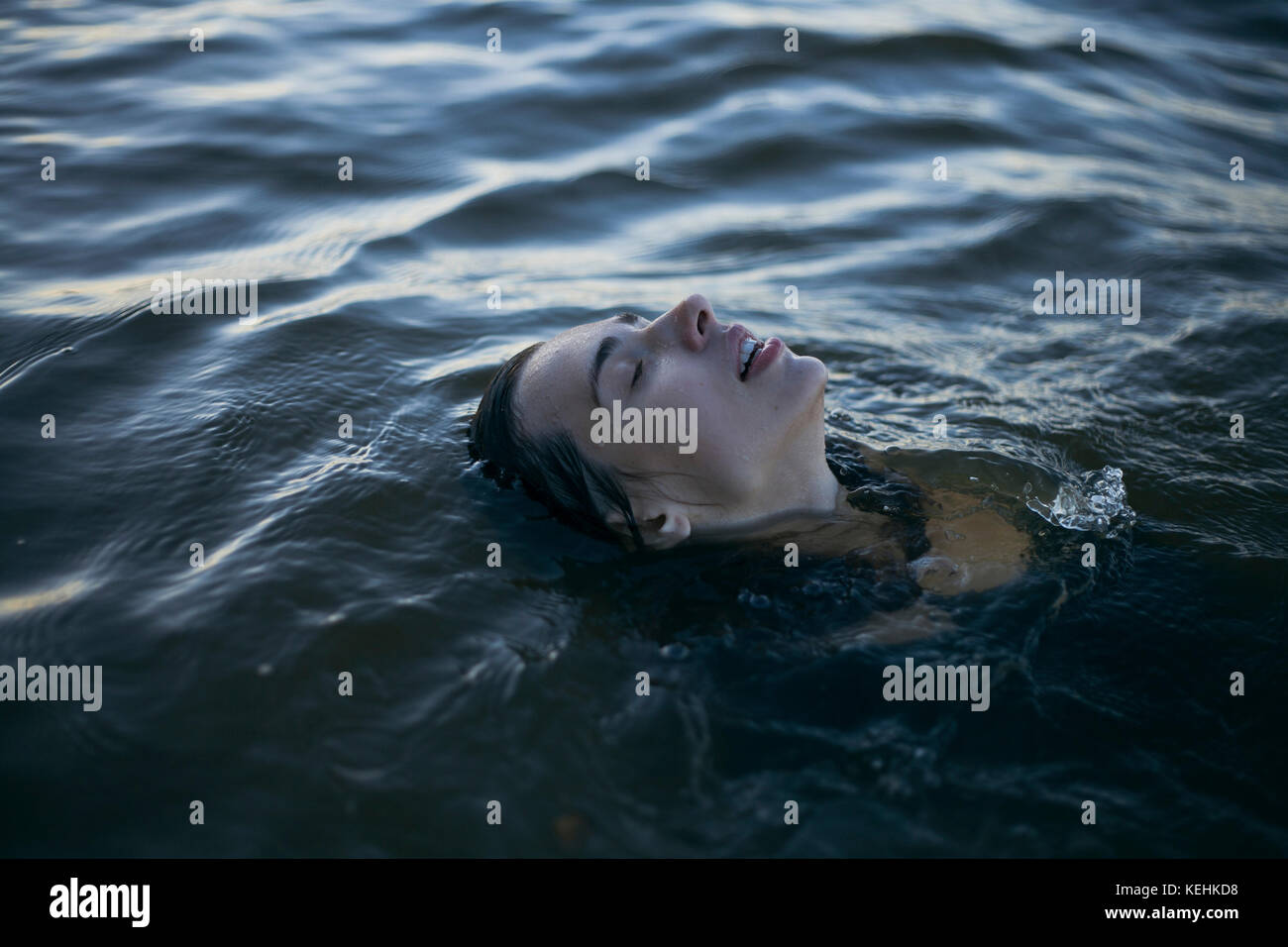 Donna caucasica che galleggia in oceano con gli occhi chiusi Foto Stock