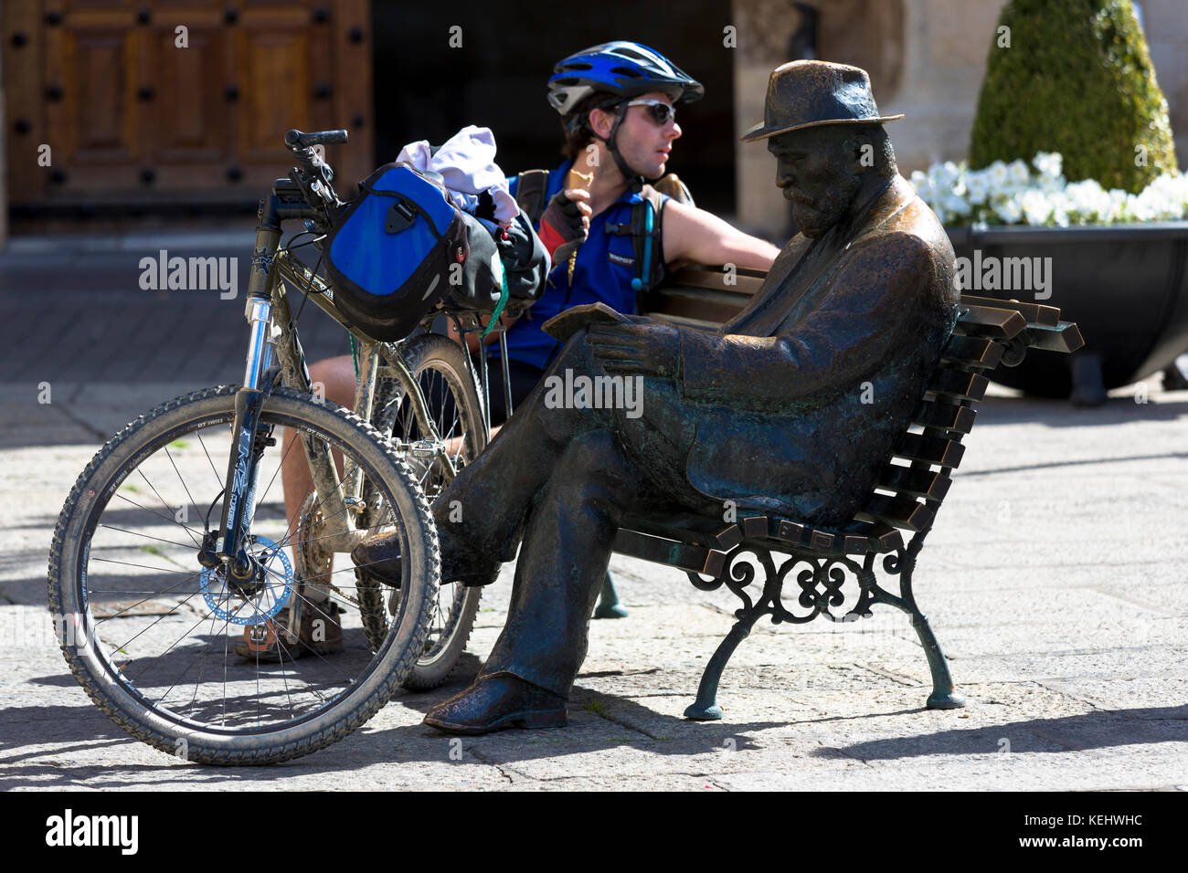 Ciclista siede dalla statua di bronzo di architetto Antoni Gaudi vicino a Caja Espana in Leon, Castilla y Leon, Spagna Foto Stock
