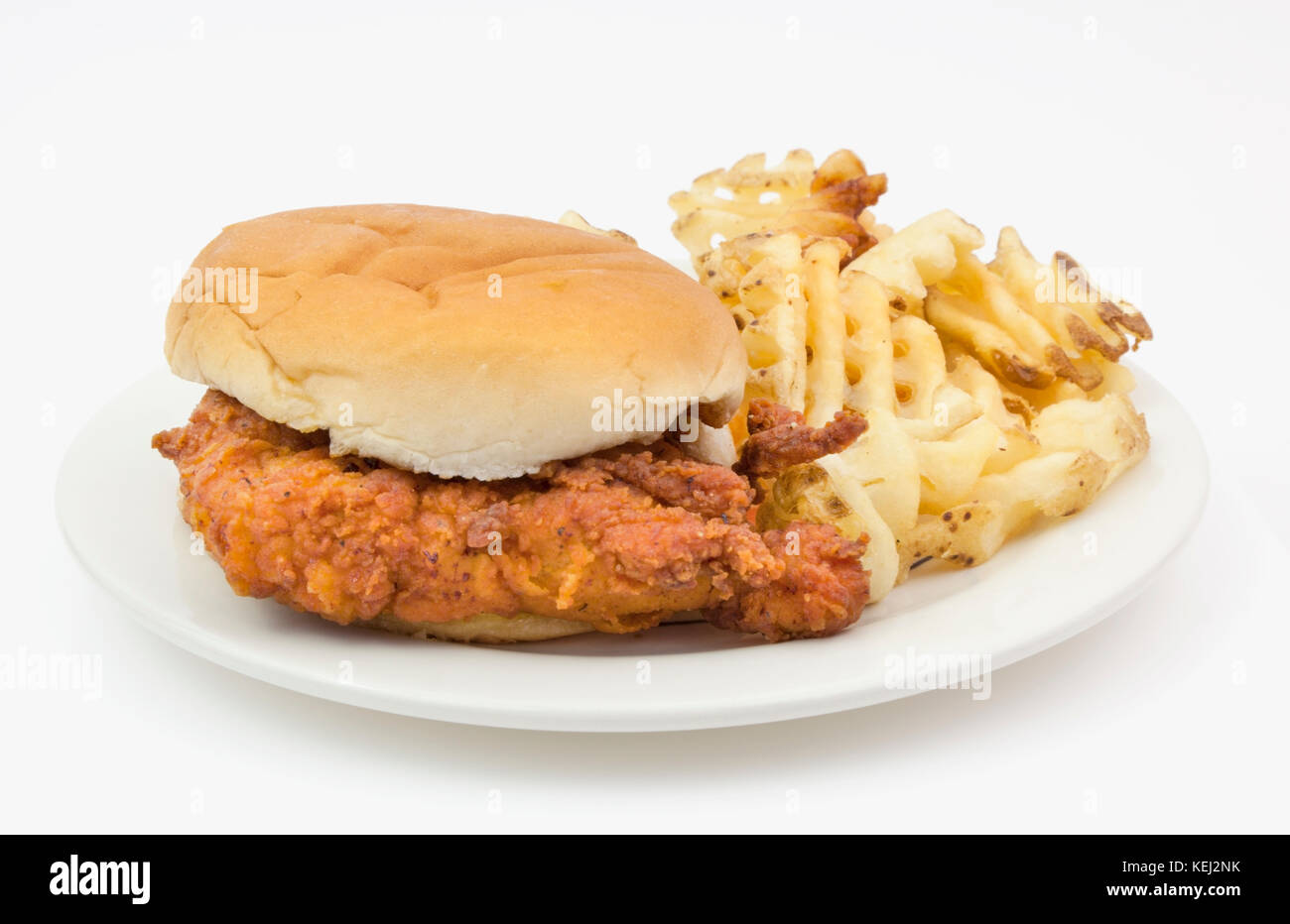Fried Chicken sandwich sulla pianura bun con waffle Patatine serviti su un foglio di carta bianca piastra. Foto Stock