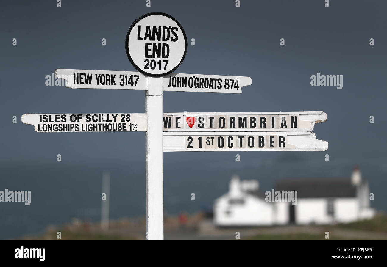 "We love Storm Brian" è visto sul cartello Land's End in Cornovaglia, mentre Storm Brian colpisce il Regno Unito con venti fino a 70 mph devastante zone costiere. Foto Stock