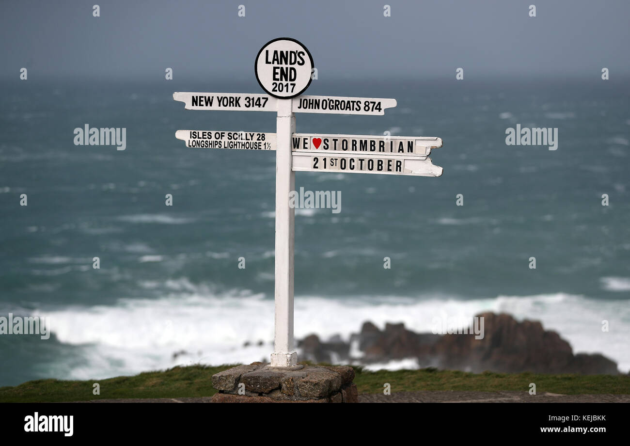 "We love Storm Brian" è visto sul cartello Land's End in Cornovaglia, mentre Storm Brian colpisce il Regno Unito con venti fino a 70 mph devastante zone costiere. Foto Stock