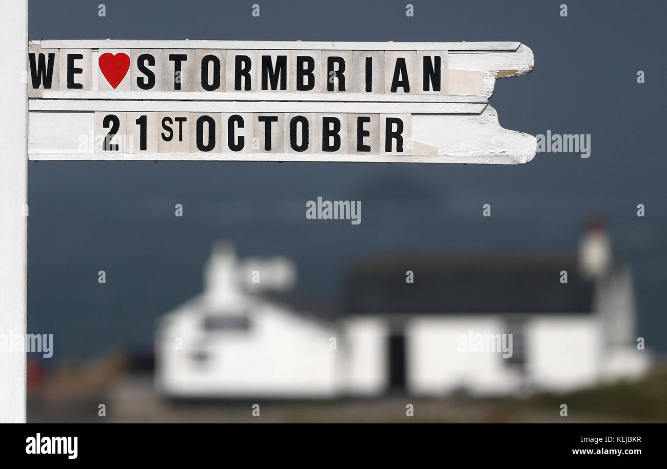 "We love Storm Brian" è visto sul cartello Land's End in Cornovaglia, mentre Storm Brian colpisce il Regno Unito con venti fino a 70 mph devastante zone costiere. Foto Stock