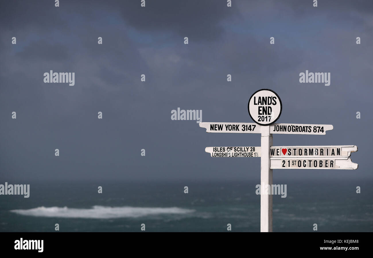 "We love Storm Brian" è visto sul cartello Land's End in Cornovaglia, mentre Storm Brian colpisce il Regno Unito con venti fino a 70 mph devastante zone costiere. Foto Stock