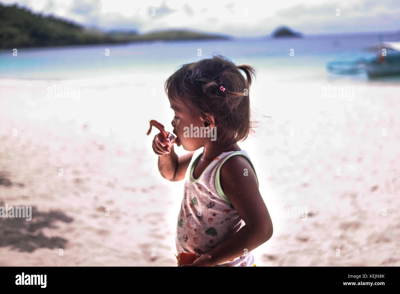 Una ragazza che mangia papaya sulla spiaggia di Calaguas. Foto Stock
