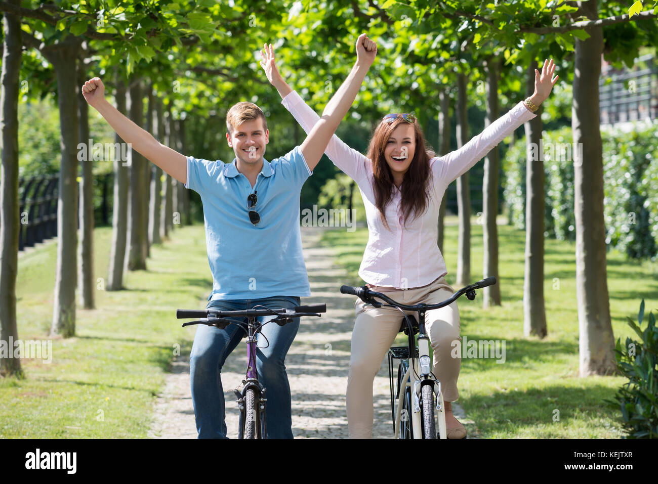 L uomo e la donna avendo divertimento sulla Bicicletta Equitazione insieme nel Parco Foto Stock