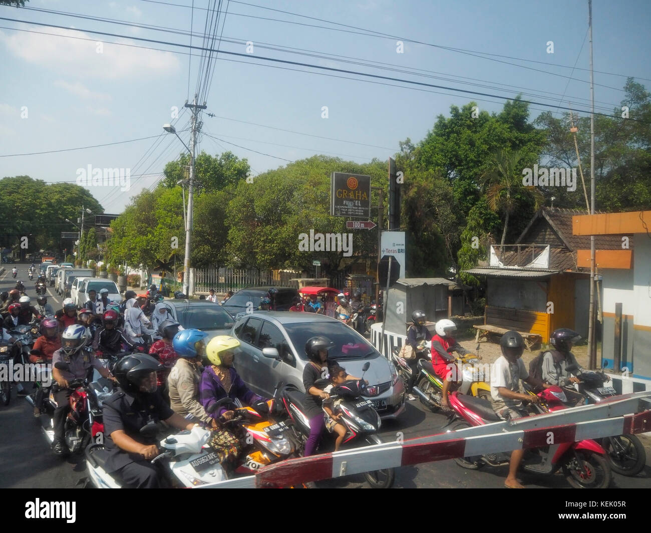 Utenti della strada in attesa di un treno che attraversa Sragen, Giava Centrale, Indonesia. Foto Stock
