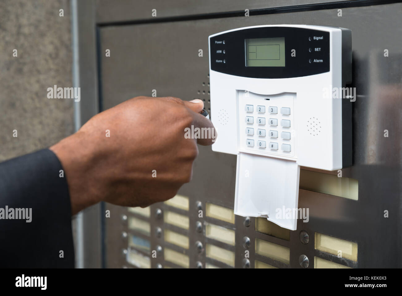 Close-up di commercianti la mano utilizzando il telecomando per il funzionamento di porte con sistema di sicurezza Foto Stock