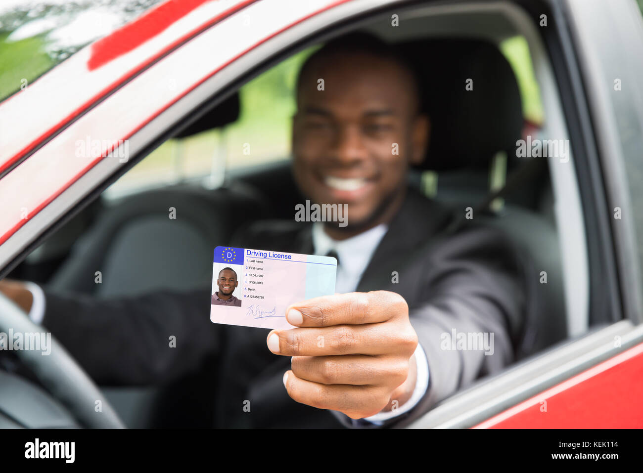 Felice giovane imprenditore africani che mostra la sua patente di guida di aprire la finestra auto Foto Stock